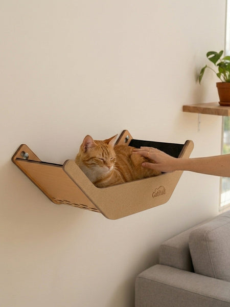 Gatitud Store wall-mounted cat hammock made of MDF and soft fabric, with an orange tabby cat resting comfortably.