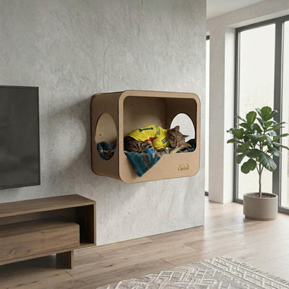 Cueva rectangular de madera MDF natural para gatos de Gatitud, con entrada redonda y manta azul. Gato durmiendo.
