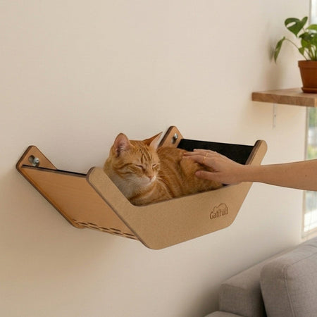 Gatitud Store wall-mounted cat hammock made of MDF and soft fabric, with an orange tabby cat resting comfortably.